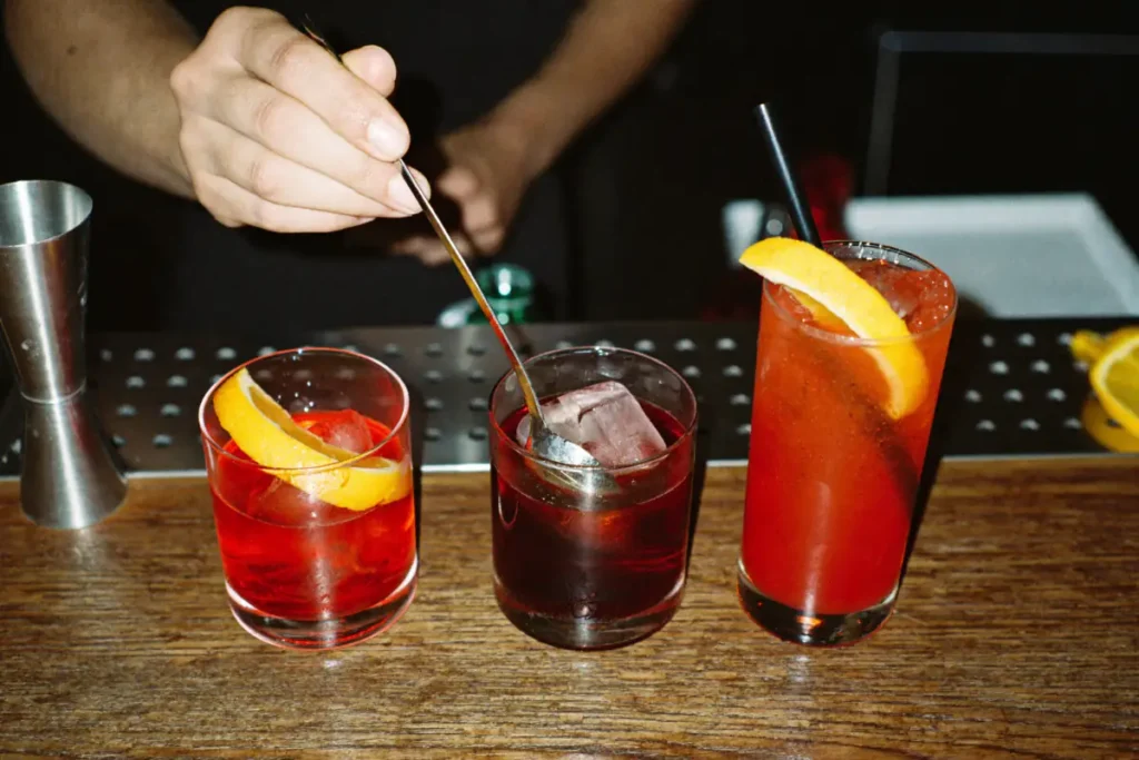 Barman qui remue un Negroni, entre un Americano et un Garibaldi au jus d'orange