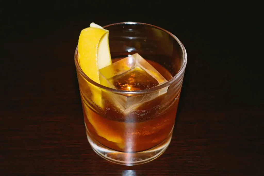 Old Fashioned ambré avec un gros glaçon et un zeste d'orange