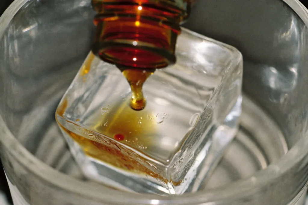 Une goutte de bitters tombe sur un gros glaçon