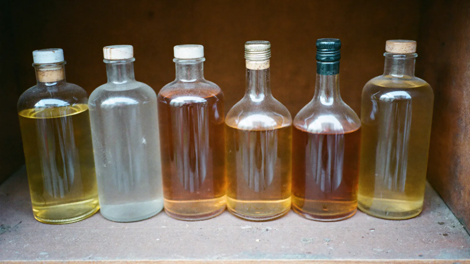 Bouteilles de spiritueux clairs et ambrés alignées sur une étagère