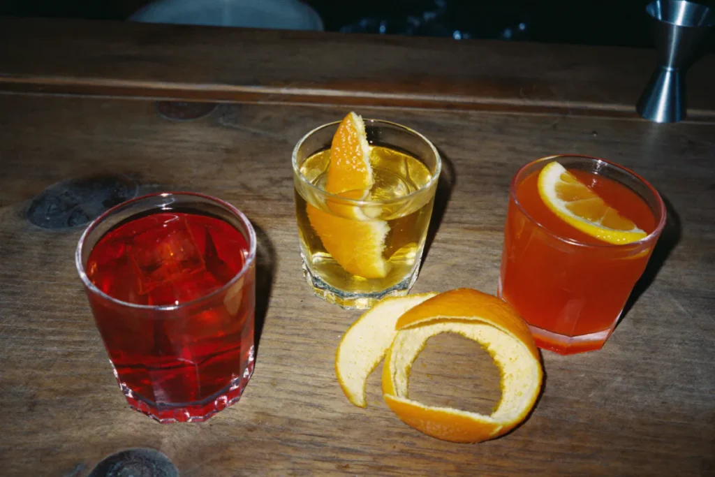 Vermouth rouge, liqueur d'orange et apéritif amer servis dans trois verres