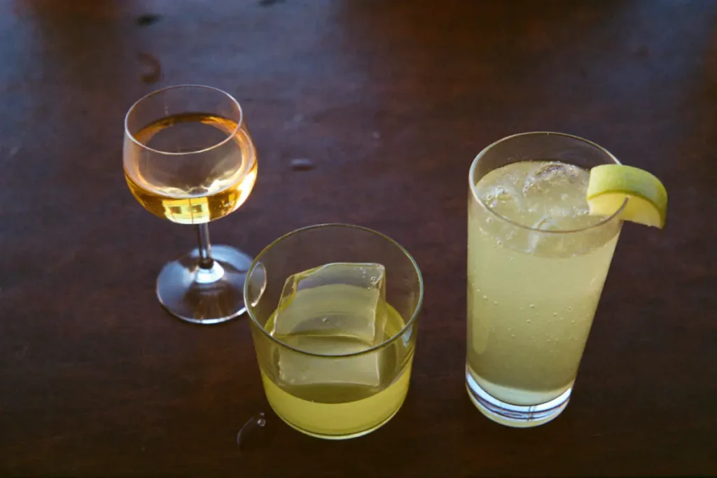 Liqueur de plantes servie de trois façons : nature, sur un gros glaçon et allongée de tonic avec un quartier de citron