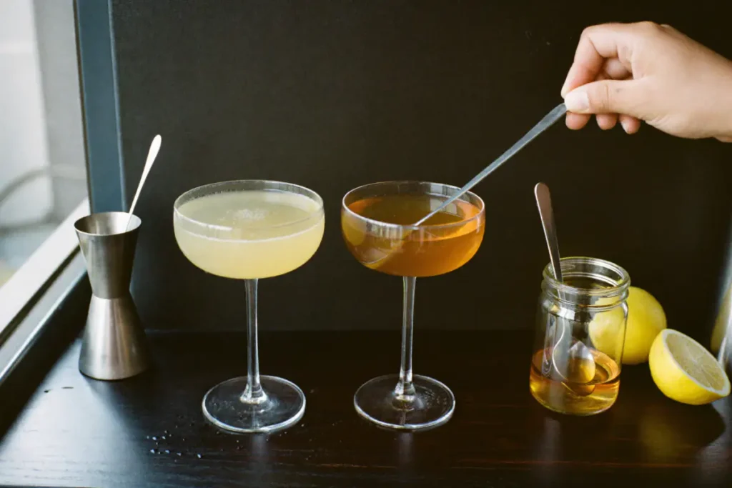 Deux sours en coupe, l'un au sirop de sucre et l'autre au miel, goûtés à la cuillère à côté d'un doseur et d'un pot de miel