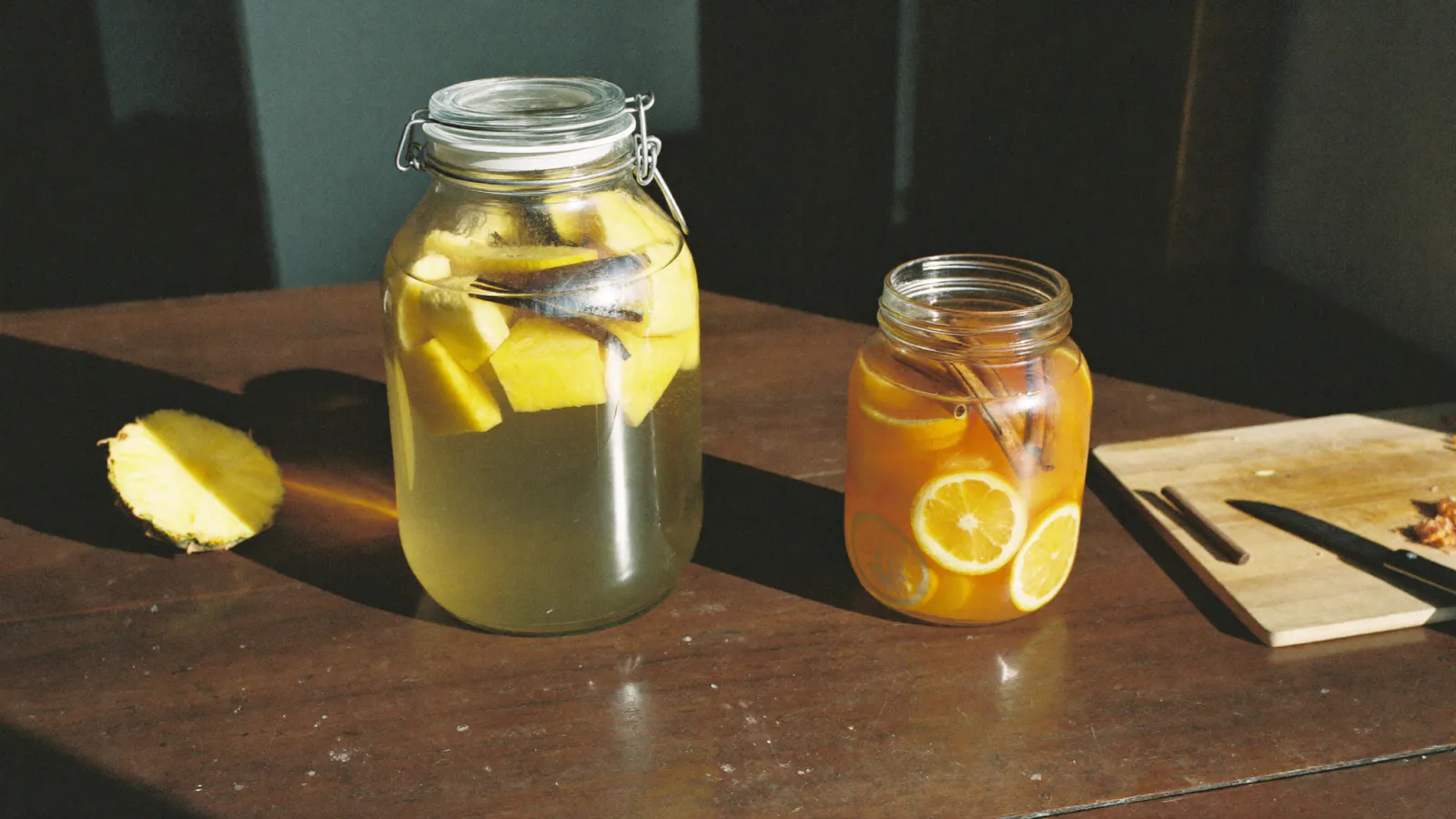 Bocaux de rhum arrangé maison à l'ananas, à la vanille et à l'orange sur une table en bois