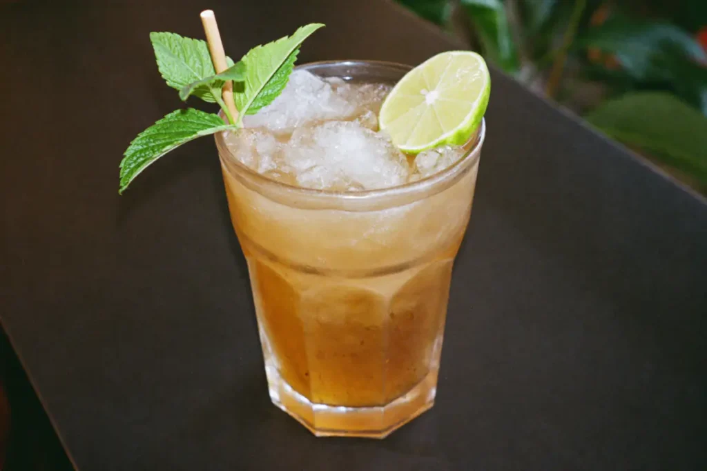 Mai Tai sur glace pilée garni de menthe fraîche et d'un demi-citron vert