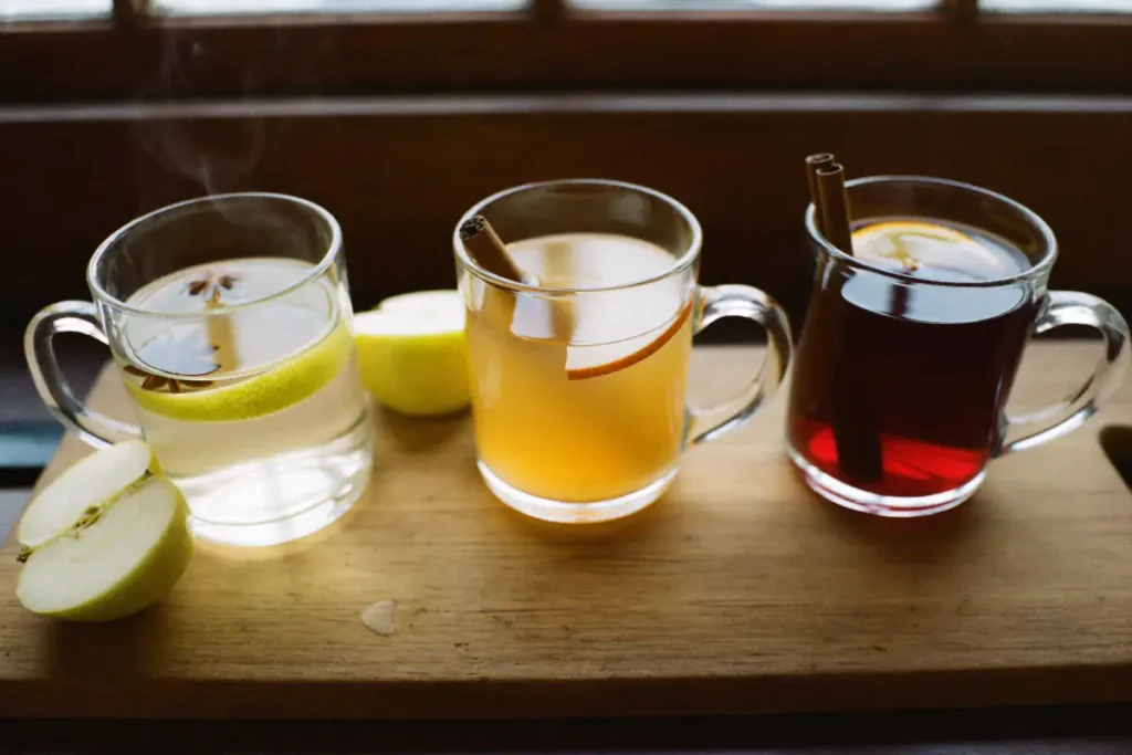 Vin chaud blanc, cidre chaud à la pomme et vin chaud sans alcool servis dans trois mugs en verre