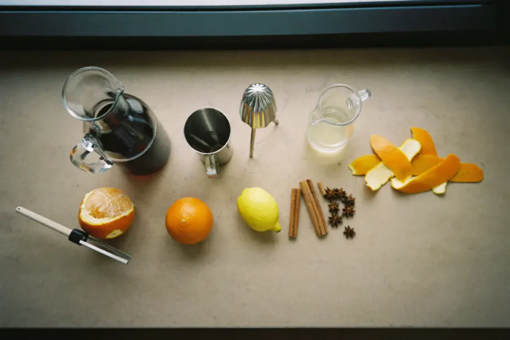 Ingrédients du vin chaud : carafe de vin rouge, oranges, citron, zestes, cannelle, badiane, sirop de sucre et jigger