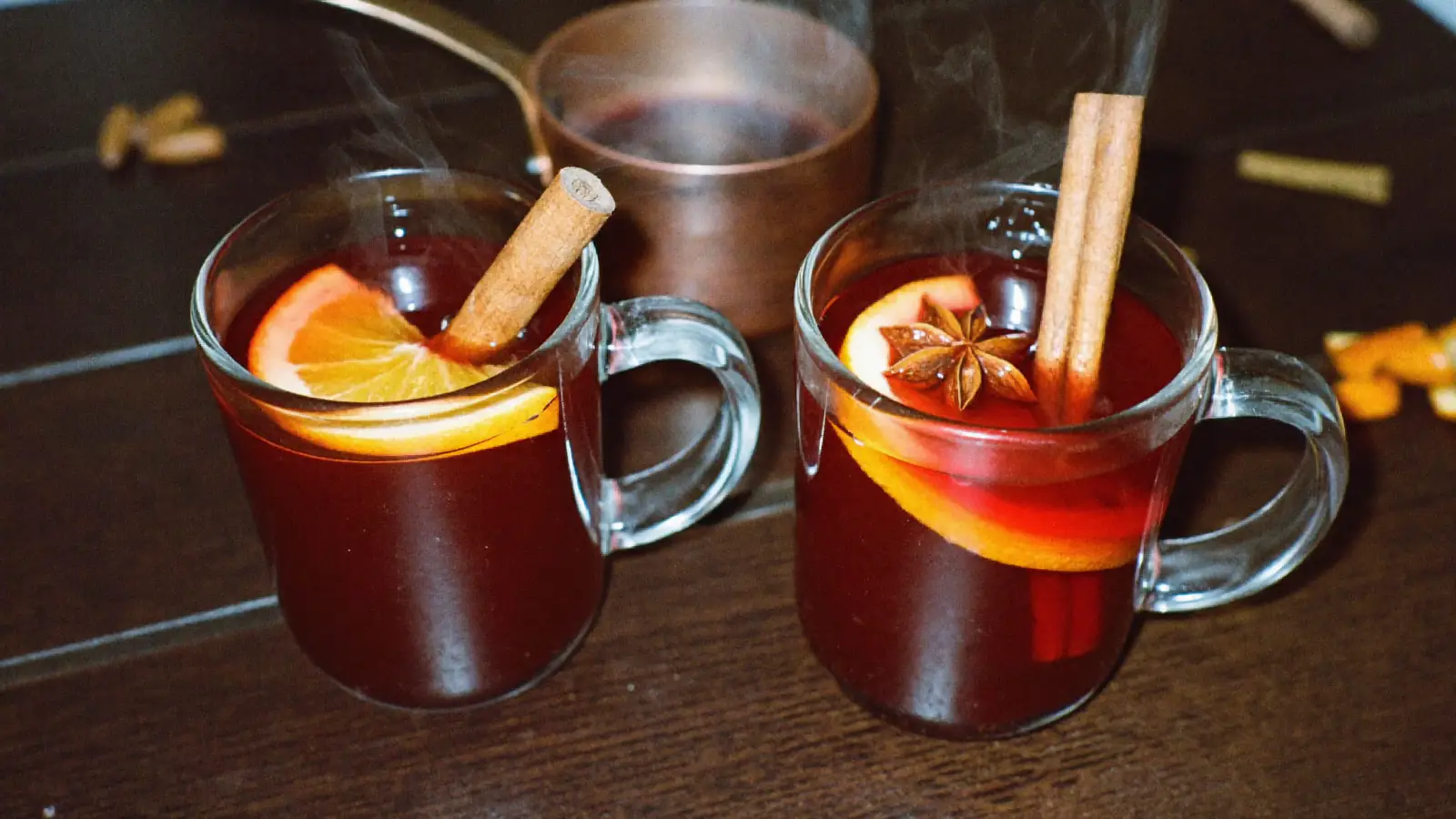 Deux mugs de vin chaud maison fumants avec une rondelle d'orange, un bâton de cannelle et une étoile de badiane